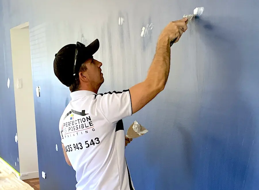 Ben filling any holes and fixing scratches on wall to prepare for painting